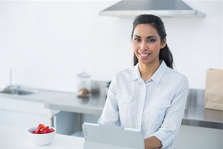 Cheerful woman working on her tablet smiling at camera standing in kitchen Stock Photo - Budget Royalty-Free & Subscription, Code: 400-07133937