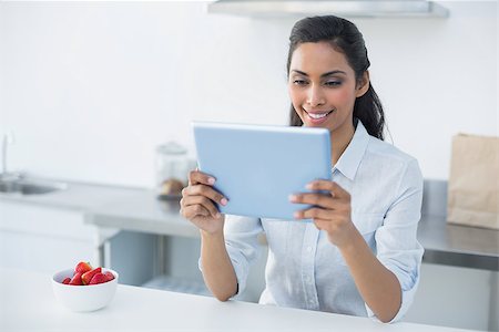 Smiling woman holding her tablet standing in bright kitchen at home Stock Photo - Budget Royalty-Free & Subscription, Code: 400-07133939
