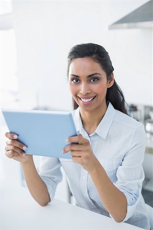 Attractive peaceful woman holding her tablet smiling cheerfully at camera standing in bright kitchen Stock Photo - Budget Royalty-Free & Subscription, Code: 400-07133941