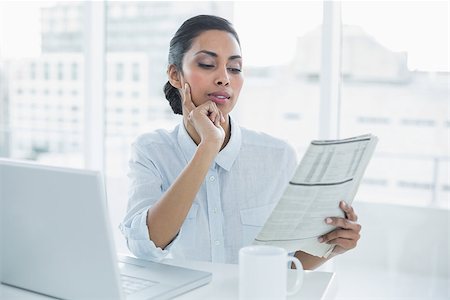 Focused businesswoman reading newspaper sitting at her desk in bright office Stock Photo - Budget Royalty-Free & Subscription, Code: 400-07133980