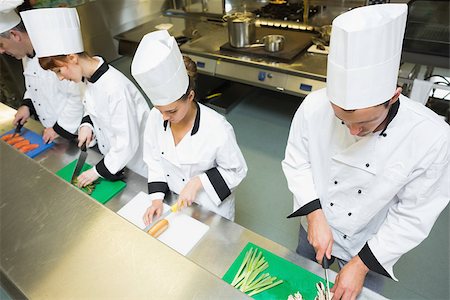 simsearch:400-07140008,k - Four chefs preparing food at counter standing in a row in a kitchen Photographie de stock - Aubaine LD & Abonnement, Code: 400-07140006