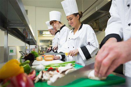 simsearch:400-07140008,k - Four chefs preparing food at counter in a row in a professional kitchen Photographie de stock - Aubaine LD & Abonnement, Code: 400-07140008