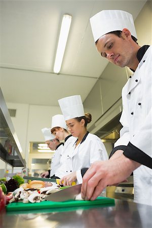 simsearch:400-07140055,k - Four chefs preparing food at counter in a row in a professional kitchen Stock Photo - Budget Royalty-Free & Subscription, Code: 400-07140009