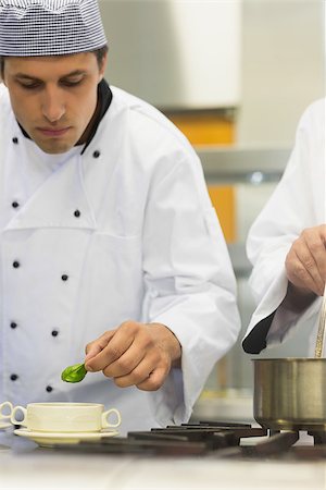 simsearch:400-07141137,k - Young male chef garnishing a bowl soup with a basil leaf in kitchen Stock Photo - Budget Royalty-Free & Subscription, Code: 400-07140018