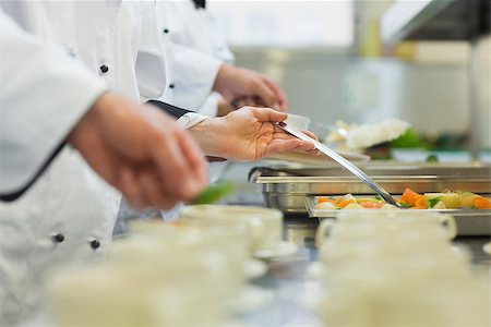 simsearch:400-07140055,k - Chefs standing in a row preparing food in a modern kitchen Stock Photo - Budget Royalty-Free & Subscription, Code: 400-07140055