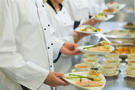 simsearch:400-07140008,k - Chef holding salmon dishes standing in a row with colleagues Photographie de stock - Aubaine LD & Abonnement, Code: 400-07140052