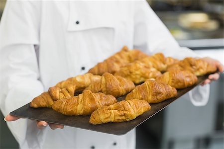 simsearch:400-07140099,k - Baker presenting some croissants on a baking tray Foto de stock - Royalty-Free Super Valor e Assinatura, Número: 400-07140078