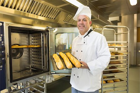 simsearch:400-07140099,k - Mature baker showing three baguettes standing in front of an oven Foto de stock - Royalty-Free Super Valor e Assinatura, Número: 400-07140088