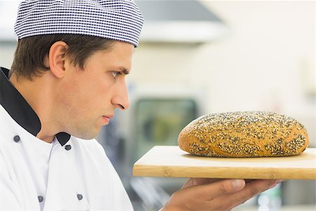 simsearch:400-07140099,k - Young baker inspecting a seeded loaf of bread in commercial kitchen Foto de stock - Royalty-Free Super Valor e Assinatura, Número: 400-07140082