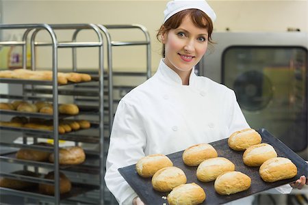 simsearch:400-07140099,k - Happy female baker showing some rolls on a baking tray smiling at the camera Foto de stock - Royalty-Free Super Valor e Assinatura, Número: 400-07140097