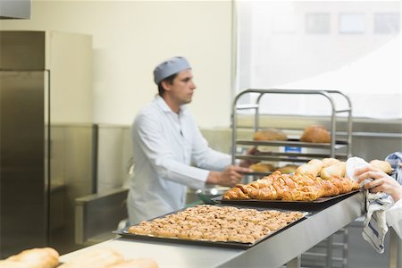 Young male baker working in a kitchen wearing a work coat Photographie de stock - Aubaine LD & Abonnement, Code: 400-07140102