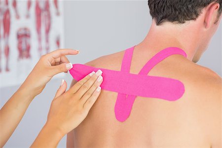 physical therapy shoulder - Physiotherapist putting on pink kinesio tape on male patients back in bright office Stock Photo - Budget Royalty-Free & Subscription, Code: 400-07140298