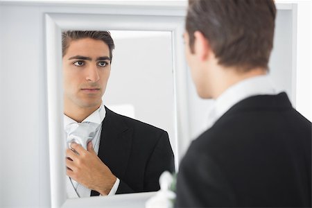 simsearch:400-04171391,k - Serious handsome bridegroom looking in mirror straightening his tie Stock Photo - Budget Royalty-Free & Subscription, Code: 400-07140321