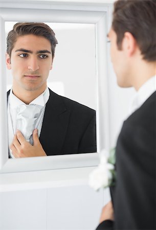 raddrizzare - Serious young bridegroom straightening his tie looking in a mirror Fotografie stock - Microstock e Abbonamento, Codice: 400-07140323