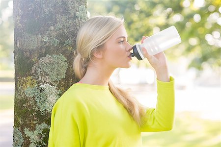 Fit peaceful blonde drinking from water bottle in a park on a sunny day Stock Photo - Budget Royalty-Free & Subscription, Code: 400-07140483