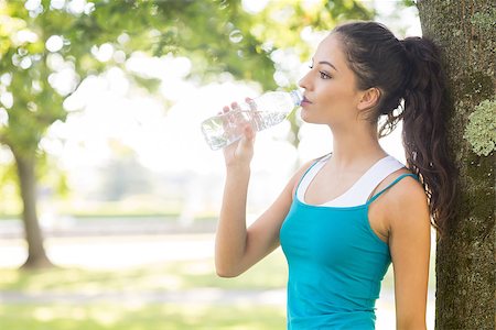 Active peaceful brunette drinking from a water bottle in a park on a sunny day Stock Photo - Budget Royalty-Free & Subscription, Code: 400-07140529