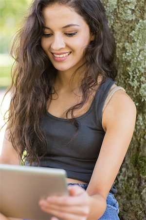 Casual cheerful brunette sitting using tablet in a park on a sunny day Stock Photo - Budget Royalty-Free & Subscription, Code: 400-07140672