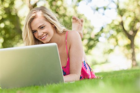 Nice young woman using her notebook lying on a lawn Stock Photo - Budget Royalty-Free & Subscription, Code: 400-07140874