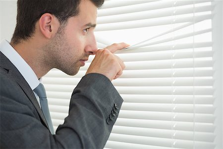 simsearch:400-07275251,k - Handsome calm businessman spying through roller blind in bright office Stock Photo - Budget Royalty-Free & Subscription, Code: 400-07141020