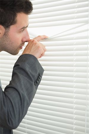simsearch:400-07275251,k - Handsome serious businessman spying through roller blind in bright office Stock Photo - Budget Royalty-Free & Subscription, Code: 400-07141021