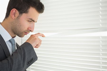 simsearch:400-07275251,k - Handsome unsmiling businessman spying through roller blind in bright office Stock Photo - Budget Royalty-Free & Subscription, Code: 400-07141022