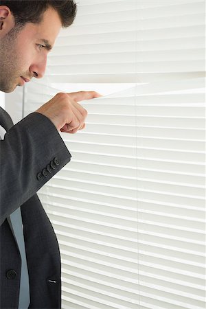 simsearch:400-07275251,k - Handsome frowning businessman spying through roller blind in bright office Stock Photo - Budget Royalty-Free & Subscription, Code: 400-07141023