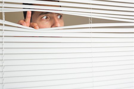 Scared beautiful brown male eyes spying through roller blind Fotografie stock - Microstock e Abbonamento, Codice: 400-07141039