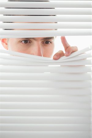 Serious beautiful brown male eyes spying through roller blind Fotografie stock - Microstock e Abbonamento, Codice: 400-07141032