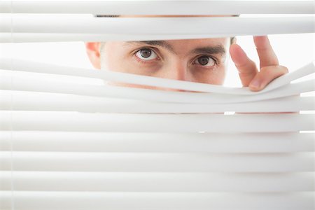 Suspicious beautiful brown male eyes spying through roller blind Fotografie stock - Microstock e Abbonamento, Codice: 400-07141033