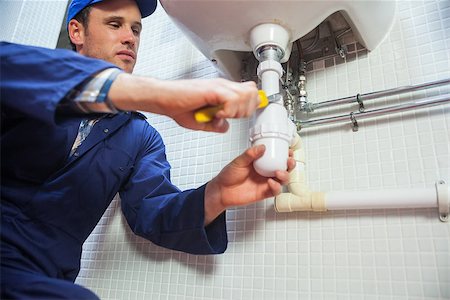 plumber - Frowning plumber repairing sink in public bathroom Stock Photo - Budget Royalty-Free & Subscription, Code: 400-07141265