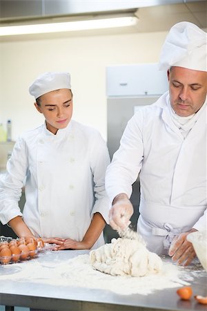 pastry chef uniform for women - Serious head chef showing trainee how to prepare dough in professional kitchen Stock Photo - Budget Royalty-Free & Subscription, Code: 400-07141299