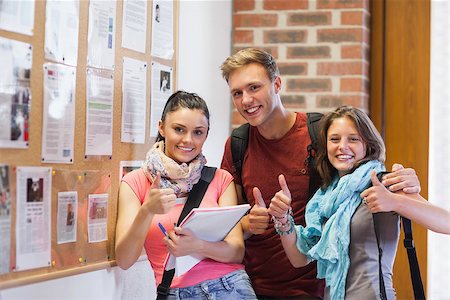 Three smiling students standing next to notice board showing thumbs up in school Stock Photo - Budget Royalty-Free & Subscription, Code: 400-07141873