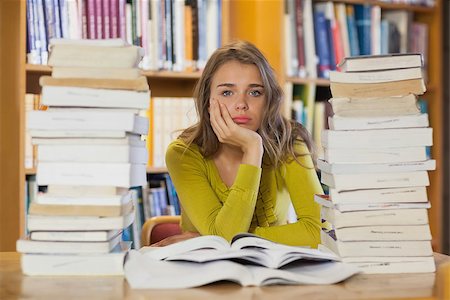 simsearch:400-07141917,k - Exhausted pretty student studying between piles of books in library Stock Photo - Budget Royalty-Free & Subscription, Code: 400-07141906