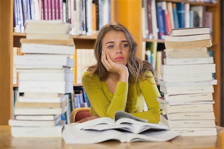simsearch:400-04295114,k - Thoughtful pretty student studying between piles of books in library Photographie de stock - Aubaine LD & Abonnement, Code: 400-07141907