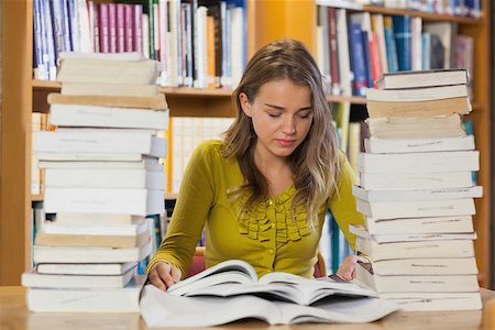 simsearch:400-07141917,k - Concentrating pretty student studying between piles of books in library Stock Photo - Budget Royalty-Free & Subscription, Code: 400-07141903