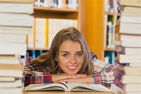 simsearch:400-04295114,k - Smiling pretty student studying between piles of books in library Photographie de stock - Aubaine LD & Abonnement, Code: 400-07141918