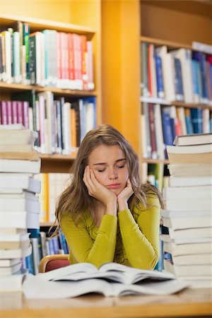 simsearch:400-04295114,k - Tired beautiful student studying between piles of books with closed eyes in library Photographie de stock - Aubaine LD & Abonnement, Code: 400-07141910