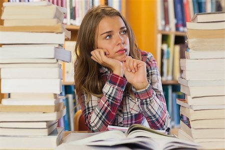 simsearch:400-04295114,k - Serious pretty student sitting between piles of books in library Photographie de stock - Aubaine LD & Abonnement, Code: 400-07141913