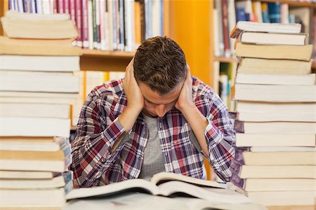 simsearch:400-07141917,k - Concentrated handsome student studying between piles of books in library Stock Photo - Budget Royalty-Free & Subscription, Code: 400-07141925