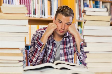 simsearch:400-04295114,k - Irritated handsome student studying between piles of books in library Photographie de stock - Aubaine LD & Abonnement, Code: 400-07141926
