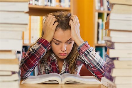 simsearch:400-04295114,k - Irritated pretty student studying between piles of books in library Photographie de stock - Aubaine LD & Abonnement, Code: 400-07141920