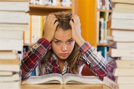 simsearch:400-04295114,k - Annoyed pretty student studying between piles of books in library Photographie de stock - Aubaine LD & Abonnement, Code: 400-07141921