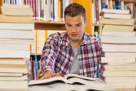 simsearch:400-04295114,k - Handsome student studying between piles of books in library Photographie de stock - Aubaine LD & Abonnement, Code: 400-07141922