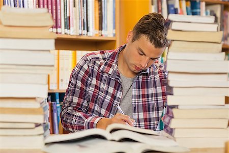 simsearch:400-07141917,k - Focused handsome student studying between piles of books in library Stock Photo - Budget Royalty-Free & Subscription, Code: 400-07141923