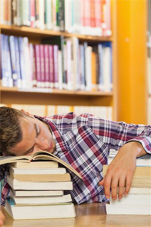 simsearch:6109-07497514,k - Exhausted handsome student resting head on piles of books in library Stockbilder - Microstock & Abonnement, Bildnummer: 400-07141931