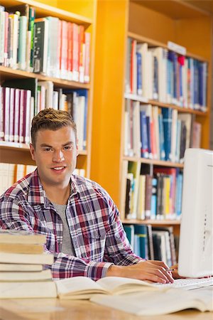 simsearch:400-07141917,k - Handsome smiling student using computer in library Stock Photo - Budget Royalty-Free & Subscription, Code: 400-07141944