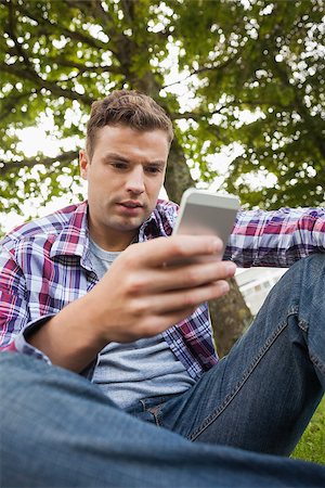students campus phones - Handsome serious student sitting on grass texting on campus at college Stock Photo - Budget Royalty-Free & Subscription, Code: 400-07142067