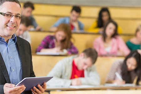 student teacher with tablet - Portrait of an elegant teacher using tablet PC with students sitting at the college lecture hall Stock Photo - Budget Royalty-Free & Subscription, Code: 400-07142560