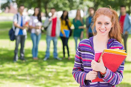 Portrait of college girl holding books with blurred students standing in the park Stock Photo - Budget Royalty-Free & Subscription, Code: 400-07142644