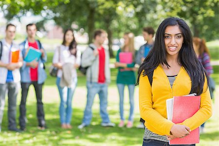 Portrait of college girl holding books with blurred students standing in the park Stock Photo - Budget Royalty-Free & Subscription, Code: 400-07142650